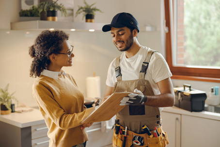 Smilng young woman signing document with plumber